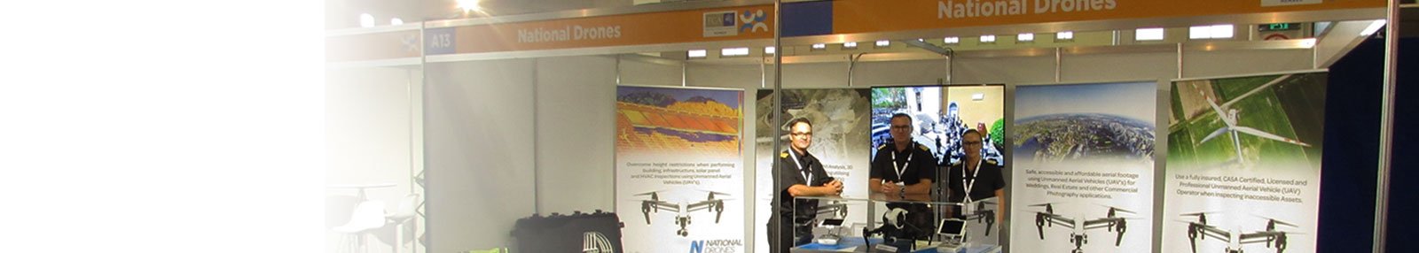 three men on the stage with drone images on the background