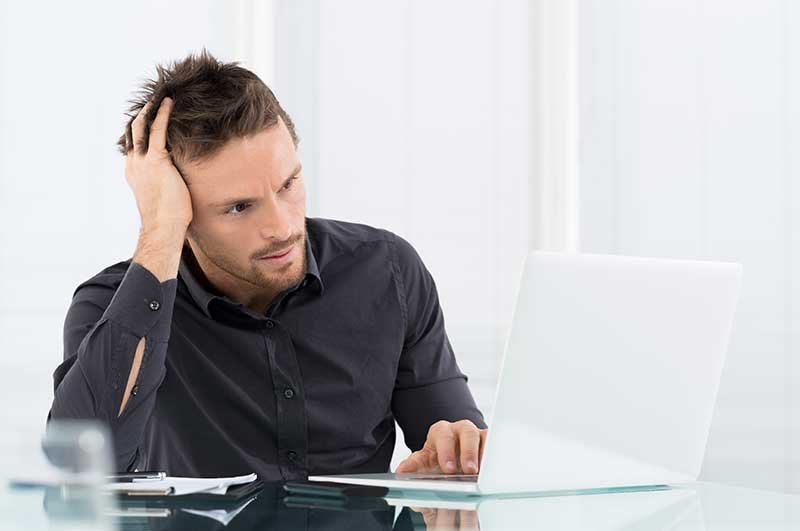 Man using a laptop, appearing to have a problem