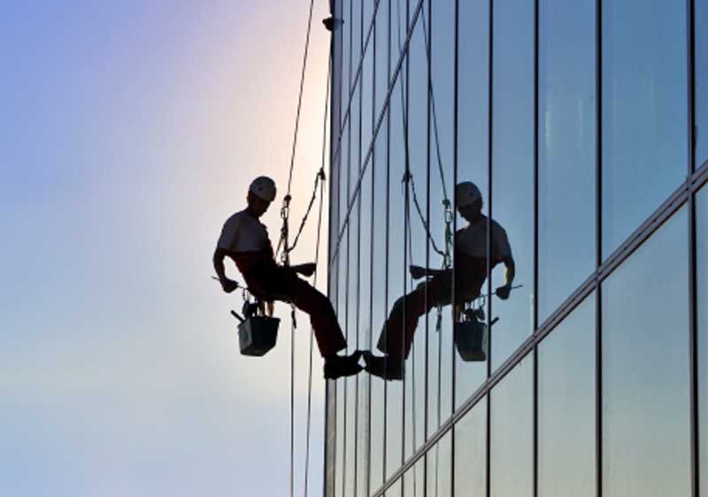 Man cleaning a window on a tall building